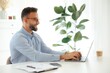 © Kateryna - Positive focused businessman typing on a laptop at a desk, while working on a project sitting in a bright modern office surrounded by charts and a cup of coffee, developing business plan, smiling