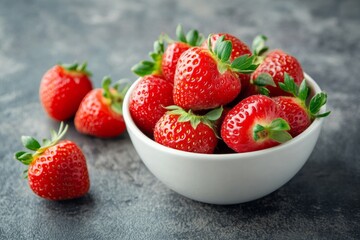 Wall Mural - Delicious strawberries collected in a white plate and lying on a gray background. The concept of tasty and healthy food