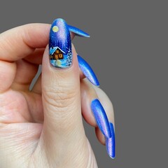 Woman's hands and fingers with modern and innovative blue nail polish for Christmas with different trendy shapes with gray background 