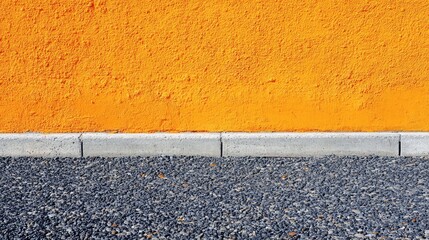 Poster - Textured orange wall with concrete curb and gravel surface creating contrast and Copy Space for design projects.