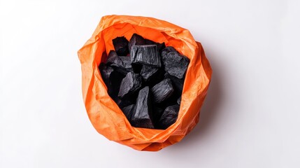 Poster - Charcoal pieces in an orange bag on white background with Copy Space for text placement