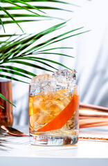 Wall Mural - North Sea oil alcoholic cocktail drink with Norwegian vodka aquavit, Italian aperitif, scotch whiskey liqueur and grapefruit twist. White marble table, palm leaves and shadows