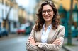 © Robbie Smith 1  - Young happy pretty smiling professional business woman, happy confident positive female entrepreneur standing outdoor on street arms crossed, looking at camera