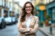 © Robbie Smith 1  - Young happy pretty smiling professional business woman, happy confident positive female entrepreneur standing outdoor on street arms crossed, looking at camera