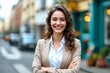 © Robbie Smith 1  - Young happy pretty smiling professional business woman, happy confident positive female entrepreneur standing outdoor on street arms crossed, looking at camera