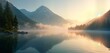 © miss irine - Misty dawn breaks over tranquil mountain lake. Serene nature landscape with rising mist. Calm water reflects mountains, trees. Peaceful, quiet scene. Picturesque view of serene nature. Perfect
