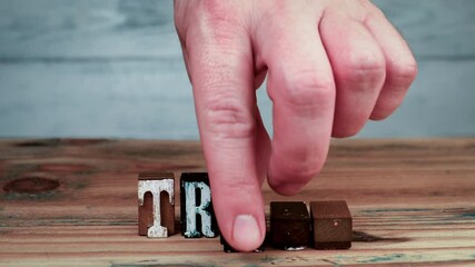 Wall Mural - TRUST. Customer or employee loyalty. The word is spelled out using wooden alphabet blocks