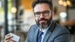 © huhu - Confident businessman holding a blank business card in a cafe.