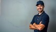 © miss irine - Confident male tech worker stands confidently against plain gray backdrop. Wears navy blue polo shirt, cap. Arms crossed. Pro, reliable image for service industry. Ideal for service company marketing