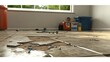 © Pannee - A broken garage floor with loose tiles, scattered screws, and a toolbox in the background