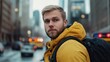 © Thiga.project - A handsome man wearing an orange jacket and black backpack stands on the street in front of emergency vehicles, with blurred city lights behind him.