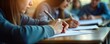 © miss irine - Students concentrate on test in classroom. Write answers on exam papers. Focused expressions, hands writing demonstrate exam day. Education vital for personal, professional growth. Classroom setting