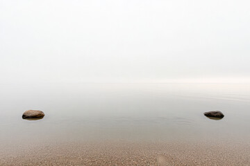 Wall Mural - Tranquil lakeside view with smooth water and foggy atmosphere in early morning