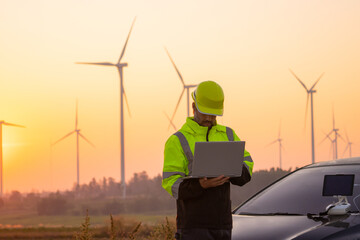 Aufkleber - Engineer working on laptop in front of wind turbines for checking wind turbines of the field during beautiful sunset. Alternative energy concept.