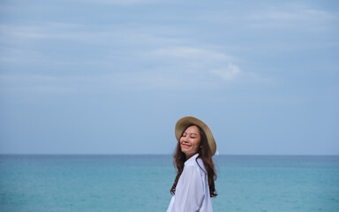 Wall Mural - Portrait image of a young woman with closed eyes standing by the sea with blue sky background