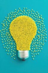 Poster - A creative arrangement of yellow beads forming a light bulb shape, symbolizing ideas and innovation against a vibrant teal background.