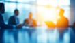 © Fareedoh - Blurred office meeting with professionals discussing strategy, illuminated by bright sunlight through windows.