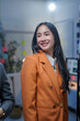 © amnaj - Asian businesswoman wearing an orange jacket is discussing a new project with colleagues in a modern office