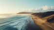 © uswatun - Aerial view of a vast ocean meeting a sandy beach with hills and soft sky in the horizon