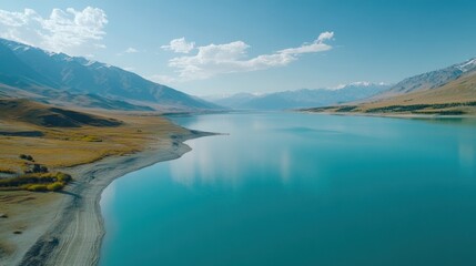 Wall Mural - Majestic mountain range and tranquil turquoise lake under clear skies with fluffy clouds