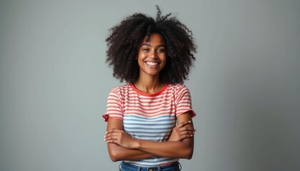 Canvas Print - A cheerful young woman with voluminous curly hair stands confidently with her arms crossed, radiating positivity. Her striped shirt adds a playful touch, enhancing the vibrant and uplifting atmosphere