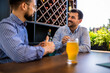 © Mediteraneo - Two male friends hanging out at the restaurant and drinking beer.