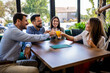 © Mediteraneo - Group of friends toasting in a restaurant with alcohol.