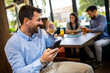 © Mediteraneo - Businessman using his phone in the restaurant. Smiling and drinking whisky.