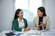 © amnaj - Two businesswomen are discussing marketing strategy analyzing charts and graphs pointing with pen in the office