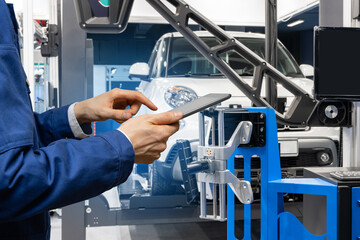 Poster - Serviceman with digital tablet on the background of the truck in the car service.