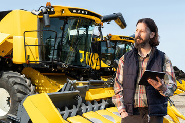 Poster - Farmer with tablet on a background of harvester. Smart farming concept