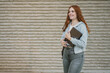 © javiindy - A Fashionable Young Woman Walking Outside with a Notebook for Studying and Inspiration
