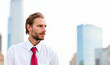 © Minerva Studio - Young businessman looking away with skyscrapers in the background