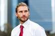 © Minerva Studio - Portrait of businessman looking away and thinking in front of skyscrapers