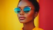 © Joachim - A stylish woman wearing trendy sunglasses poses confidently against a vibrant and colorful background, showcasing modern fashion and self-assured expression.