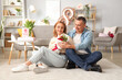 © Pixel-Shot - Middle-aged couple with bouquet of flowers sitting on floor at home. International Women's Day