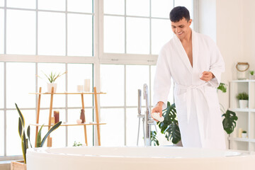 Wall Mural - Young man pouring foam into bathtub at home