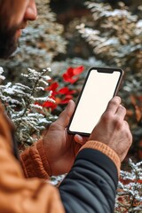 Poster - Closeup, a man checks his mobile phone on a snowy winter day. Blank white screen for mockup design.