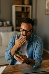 Wall Mural - Caucasian man having a video call on his smatphone through earphones in a modern home