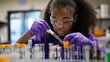 © Jaroon - A young girl wearing a purple lab coat and purple gloves is working in a lab. She is carefully pouring a liquid into a beaker. Concept of focus and concentration as the girl performs her experiment