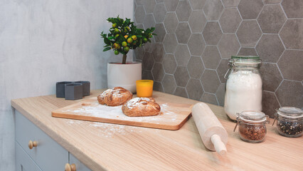 Poster - A wooden cutting board with two loaves of bread on it and a rolling pin. A potted plant is on the counter next to the bread