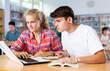 © JackF - Teenage students help each other study at laptop while sitting in the school library