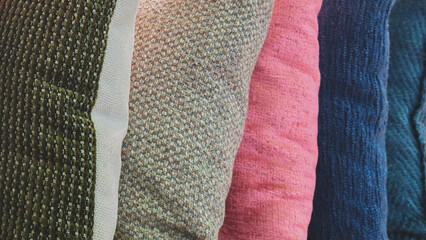 Poster - A row of pillows with different colors and textures. The pillows are arranged in a way that they are all visible, but not overlapping. The colors of the pillows are green, pink, blue, and white