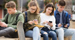 © JackF - Teenage schoolers boys and girls using their gadgets outside on sunny day