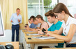 © JackF - Teenager students sitting in class room and using their smartphones.