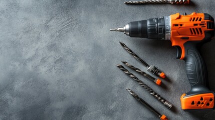 Poster - A flat-lay view of an electric drill with multiple bits arranged neatly on a smooth grey background.