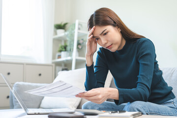 Wall Mural - Debt and financial concept, stressed asian young woman have a headache while female calculate expenses, income and expenses, looking bills of credit card for payment or payday on table at home office.