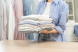 © KMPZZZ - Feel softness, chore of asian young woman, girl hand holding pile clothing from table, stack folding clean clothes after washing, laundry and dry. Household working at home. Laundry of maid concept.