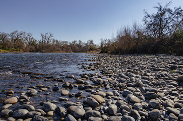 Poster - Shoreline of the American river with smooth rocks in winter 