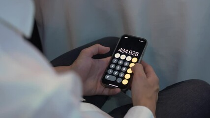 Closeup of hands using a calculator app on a smartphone, highlighting technology and productivity in action